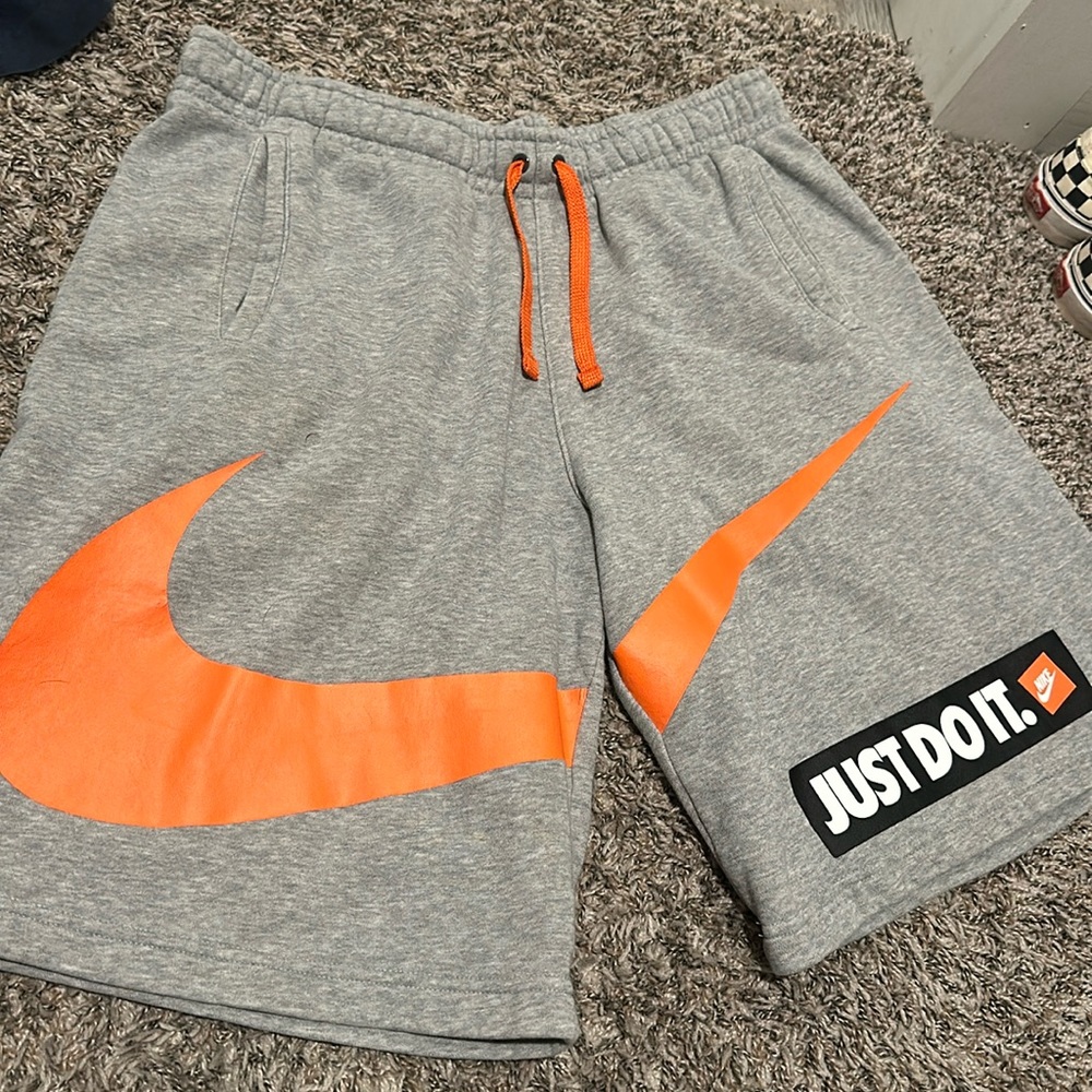 Grey Nike shorts with an orange swoosh on front and one pocket on the back side!